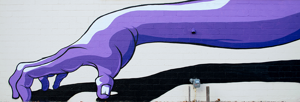 Purple arm mural on brick wall