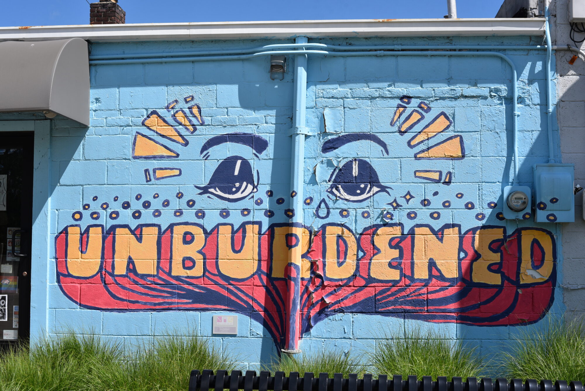 Colorful mural with eyes and word 'Unburdened'.