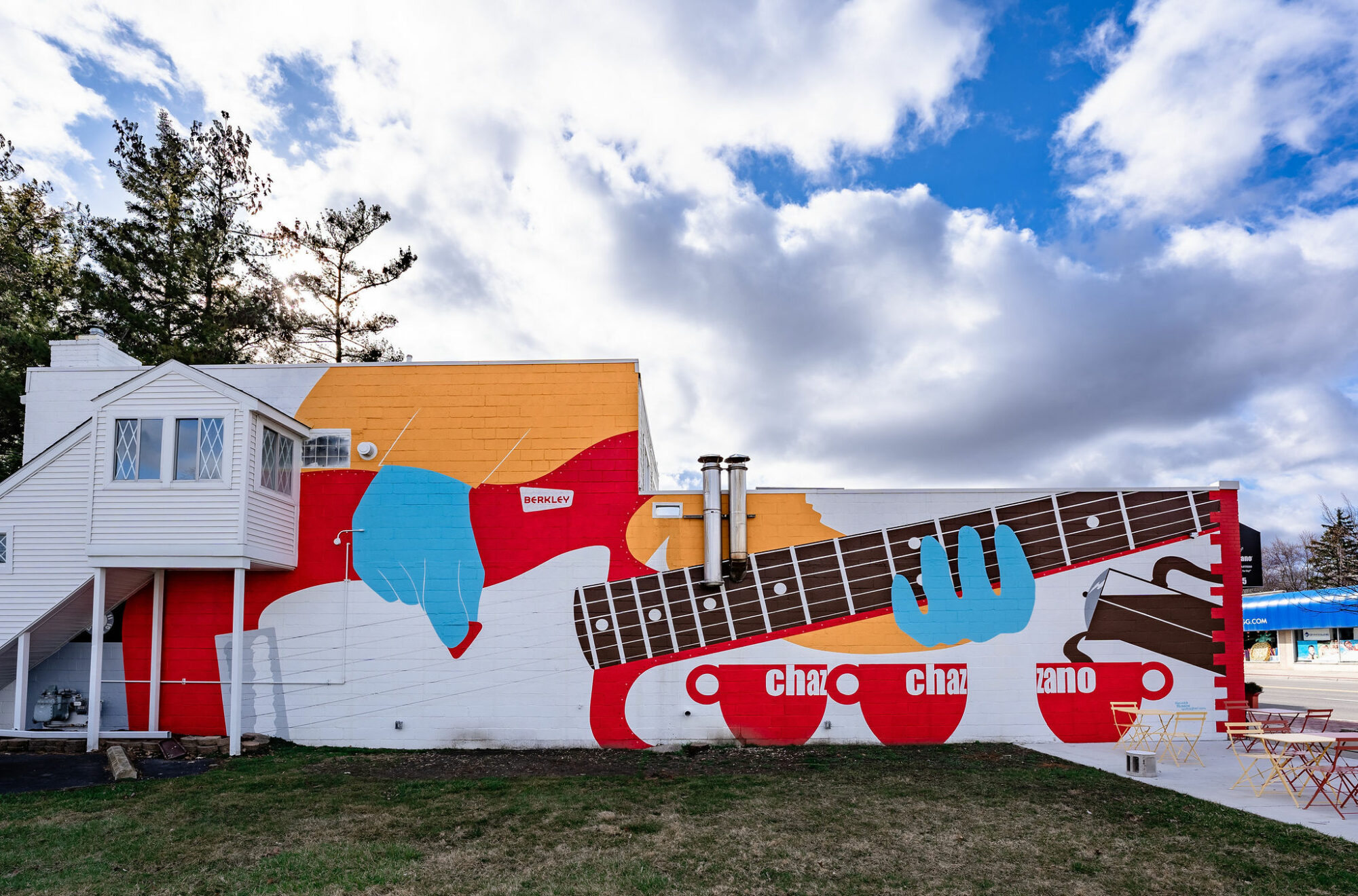Colorful mural of guitar, cups, and hand on wall.