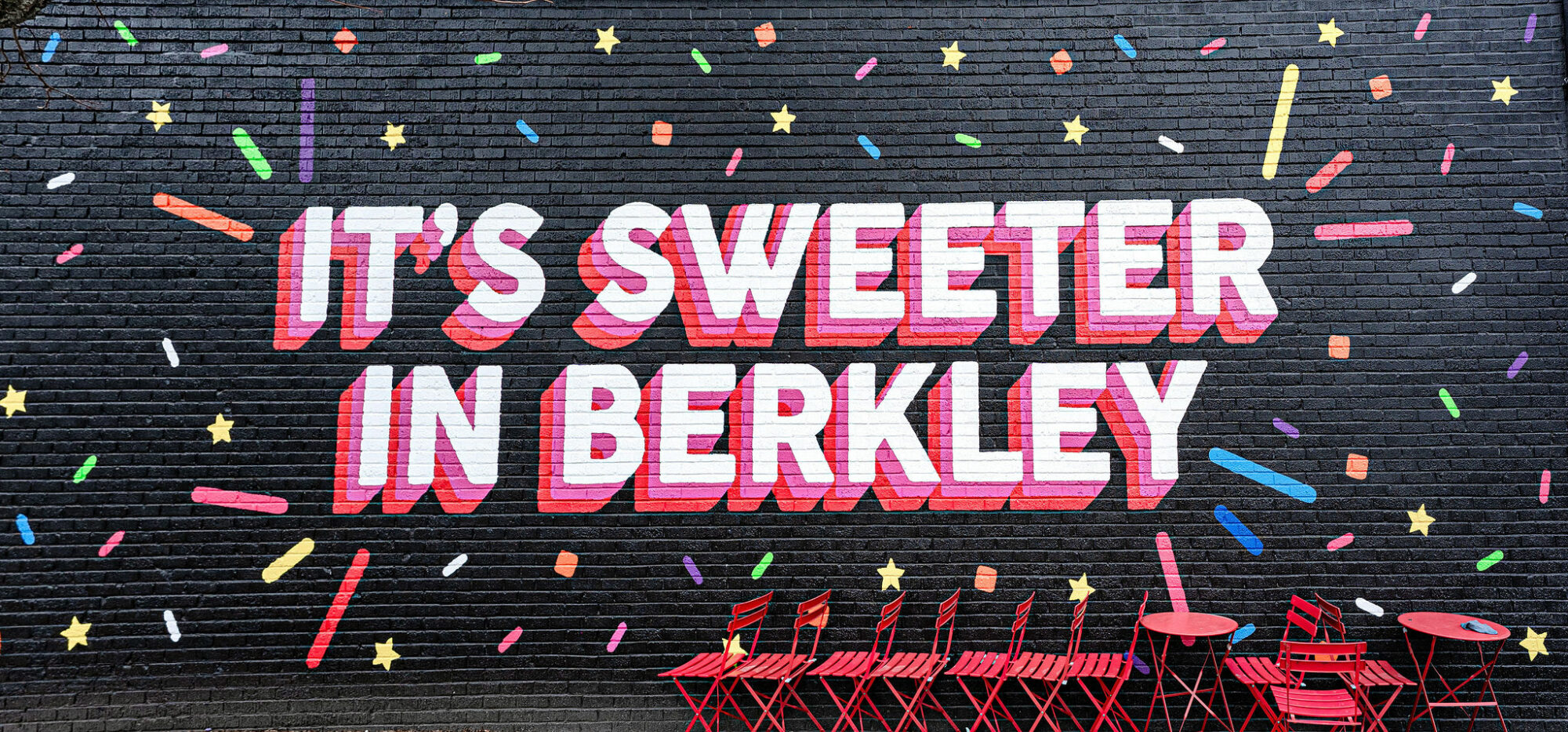 Colorful mural with confetti and red chairs.
