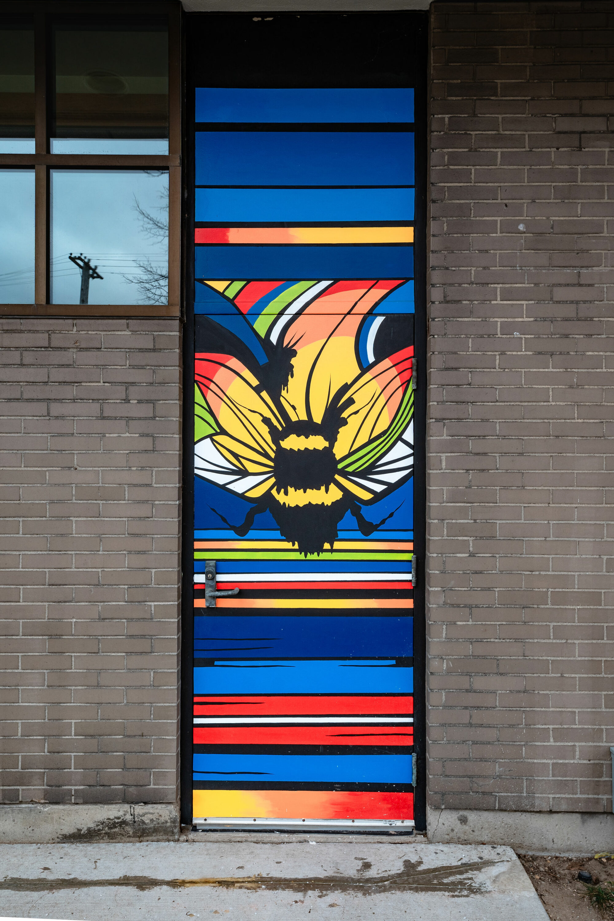 Colorful bee mural on building door.