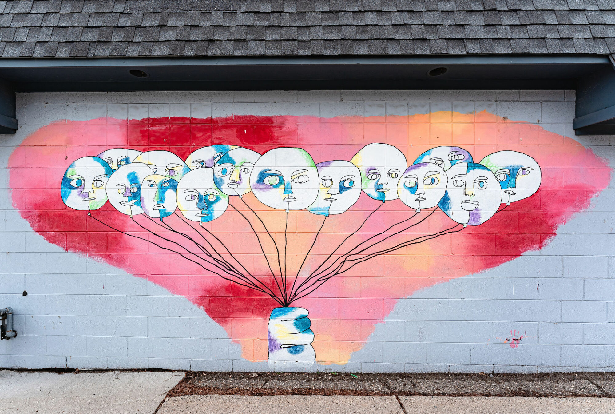 Colorful face balloons mural with hand on wall.