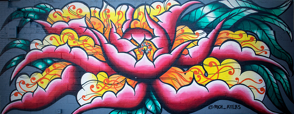 Colorful floral graffiti mural on brick wall.