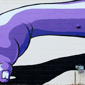 Purple arm mural on brick wall
