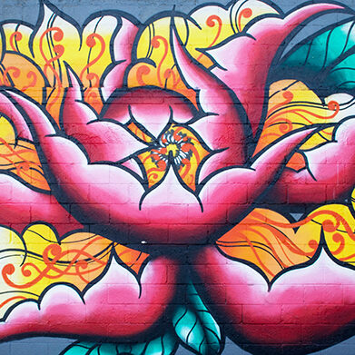 Colorful floral graffiti mural on brick wall.
