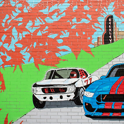 Colorful mural of racing cars on brick wall.